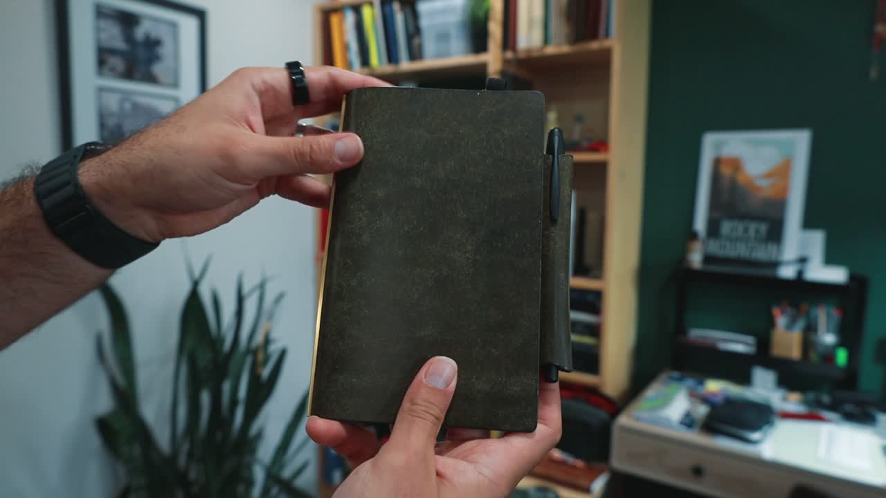 MeePlus SlimPad. Olive leather 6-ring SlimPad held in hand, gilt page edge and pen loop; opened to a 2026 year-at-a-glance insert on gold rings.